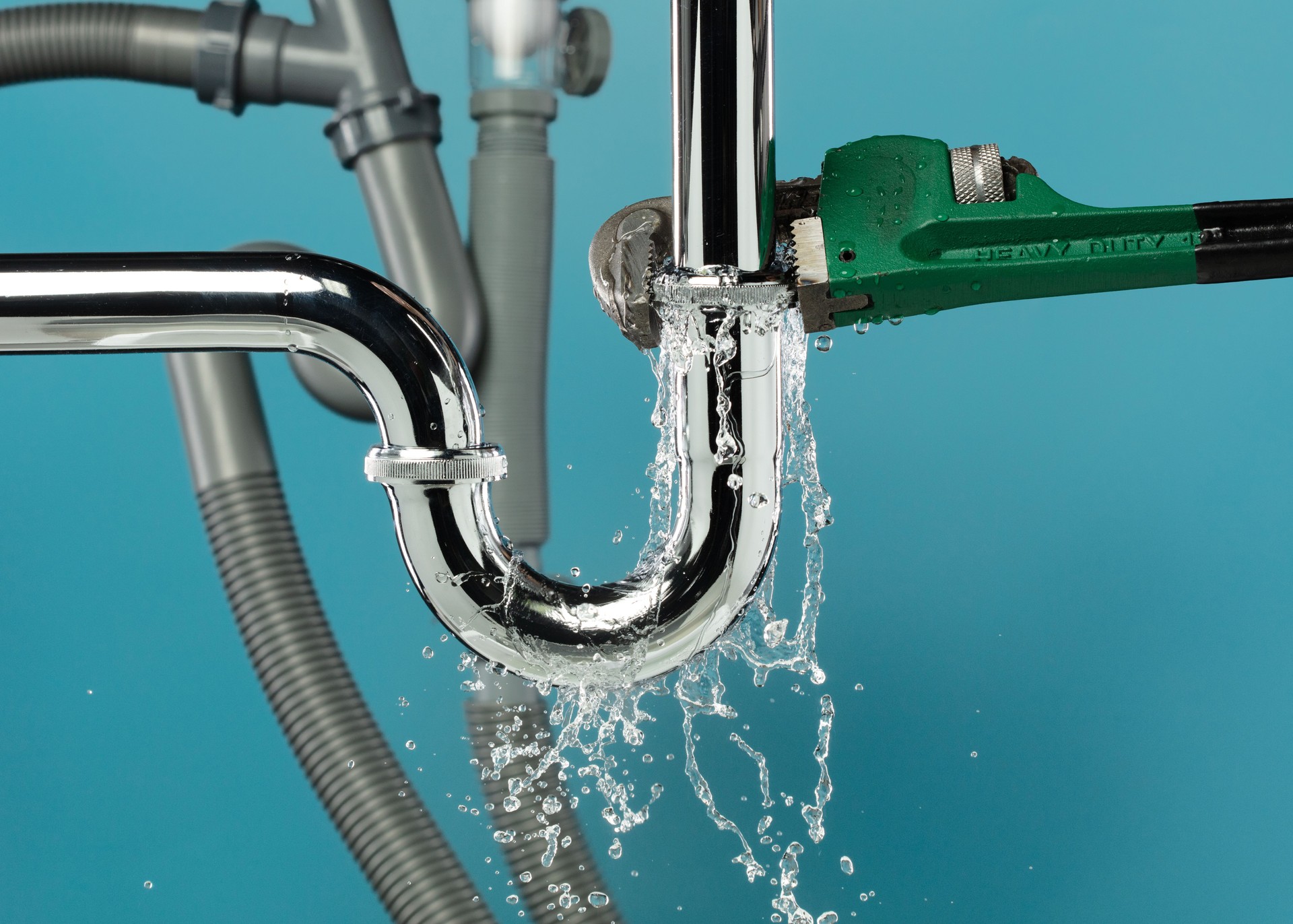 Heavy Duty Wrench fix Water leak under sink. Drain sink leak water from many pipe hose plumbing in bathroom and repair by wrench tools as water splash drop. Blue background isolated
