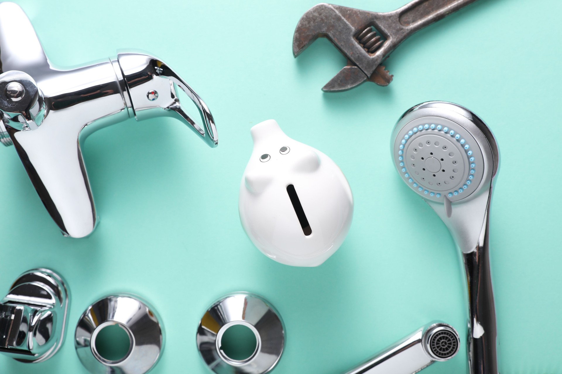 Piggy bank with parts of bath faucet and wrench on blue background. Save money